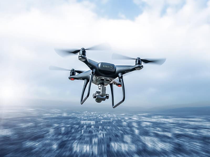 UAS drone capturing aerial data during flight over a developed area.